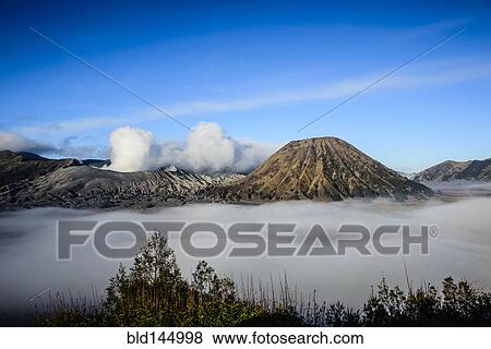 Stock Photo - High angle view of clouds under smoking volcano. Fotosearch