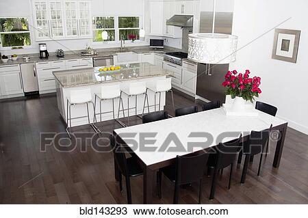 Stock Image - High angle view of tables in dining room and kitchen area. Fotosearch