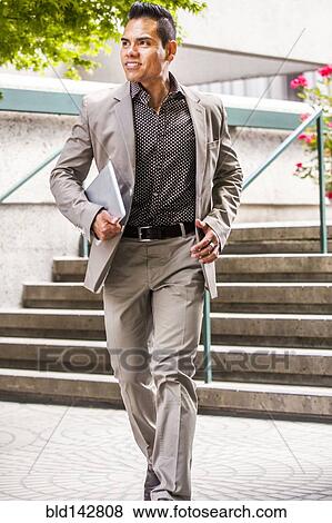 Stock Photo - Hispanic businessman carrying digital tablet near staircase. Fotosearch