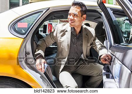 Stock Image - Hispanic businessman exiting taxi. Fotosearch