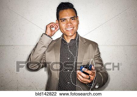 Stock Image - Hispanic businessman listening to earbuds with cell phone. Fotosearch