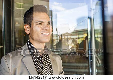 Stock Photo - Hispanic businessman looking out window. Fotosearch