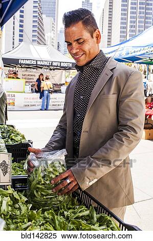 Stock Photography - Hispanic businessman shopping at urban farmers market. Fotosearch