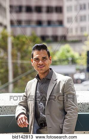 Stock Image - Hispanic businessman smiling in city. Fotosearch
