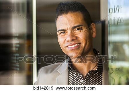 Stock Photo - Hispanic businessman smiling near window. Fotosearch