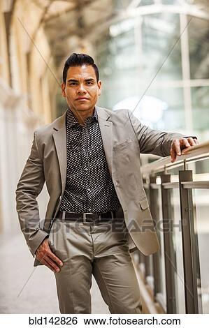Stock Photograph - Hispanic businessman standing near banister. Fotosearch