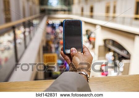 Hispanic businessman taking cell phone photograph from upper level View Large Photo Image Stock Image - Hispanic businessman taking cell phone photograph from upper level. Fotosearch