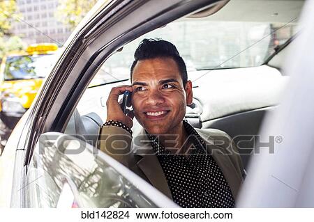 Hispanic businessman talking on cell phone in back seat of car View Large Photo Image Picture - Hispanic businessman talking on cell phone in back seat of car. Fotosearch