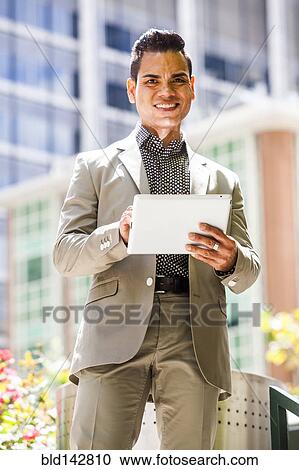 Stock Image - Hispanic businessman using digital tablet outdoors. Fotosearch