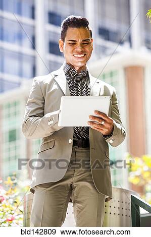 Hispanic businessman using digital tablet outdoors View Large Photo Image Stock Photo - Hispanic businessman using digital tablet outdoors. Fotosearch