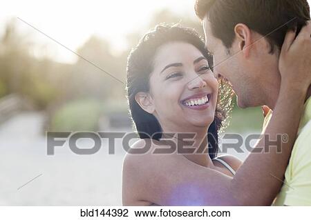 Stock Image - Hispanic couple embracing on beach. Fotosearch