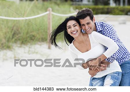 Stock Image - Hispanic couple hugging outdoors. Fotosearch