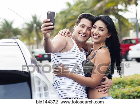 Hispanic couple taking cell phone selfie outdoors View Large Photo Image Stock Image - Hispanic couple taking cell phone selfie outdoors. Fotosearch