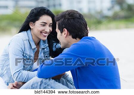 Picture - Hispanic couple talking on beach. Fotosearch