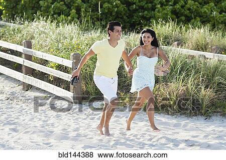 Stock Photo - Hispanic couple walking on beach. Fotosearch
