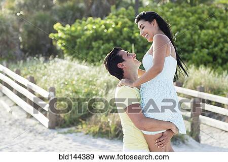 Hispanic man carrying girlfriend on beach View Large Photo Image Stock Photo - Hispanic man carrying girlfriend on beach. Fotosearch