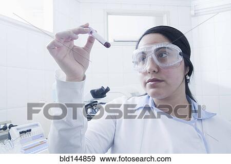 Stock Photo - Hispanic scientist examining blood sample in laboratory. Fotosearch