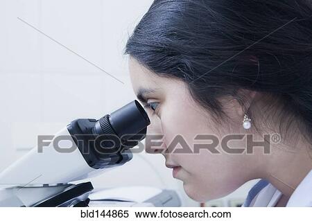 Stock Photography - Hispanic scientist using microscope in laboratory. Fotosearch