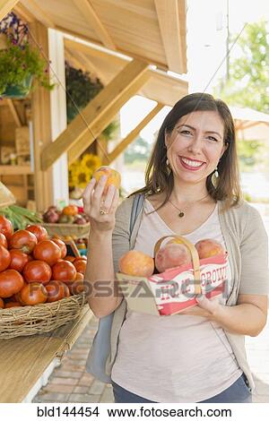 Hispanic woman holding produce at farmers market View Large Photo Image Picture - Hispanic woman holding produce at farmers market. Fotosearch