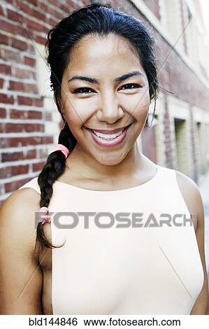 Stock Photograph - Hispanic woman smiling in city. Fotosearch