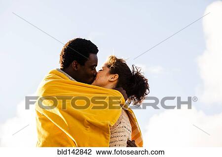 Kissing couple wrapped in blanket outdoors View Large Photo Image Stock Image - Kissing couple wrapped in blanket outdoors. Fotosearch