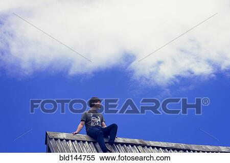 Low angle view of Caucasian boy sitting on tin roof View Large Photo Image Stock Photography - Low angle view of Caucasian boy sitting on tin roof. Fotosearch