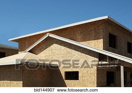 Stock Photo - Low angle view of chip board walls of house under construction. Fotosearch