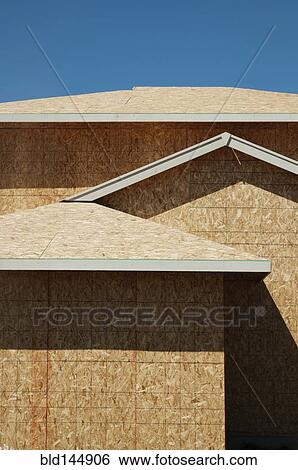 Stock Photograph - Low angle view of chip board walls of house under construction. Fotosearch