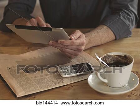 Man using digital tablet with cup of coffee View Large Photo Image Picture - Man using digital tablet with cup of coffee. Fotosearch