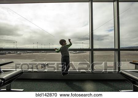 Stock Image - Mixed race boy looking out airport window. Fotosearch