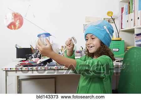 Stock Image - Mixed race girl doing science experiments at desk. Fotosearch