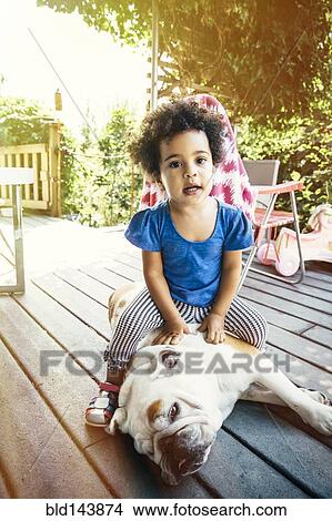 Mixed race girl sitting on dog on porch View Large Photo Image Picture - Mixed race girl sitting on dog on porch. Fotosearch