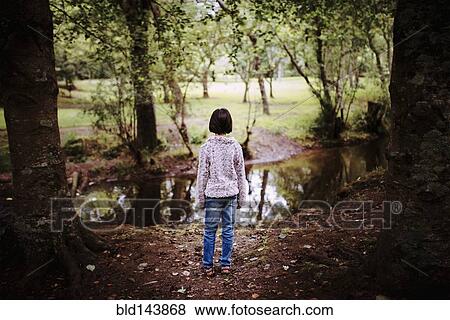 Stock Photo - Mixed race girl standing near still creek. Fotosearch