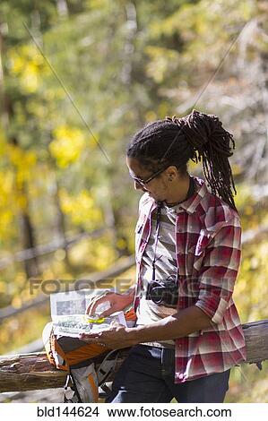 Picture - Mixed race hiker reading map in forest. Fotosearch