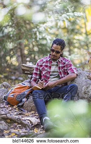 Stock Photograph - Mixed race hiker writing in forest. Fotosearch