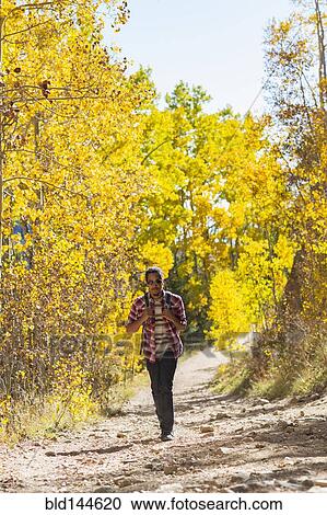 Stock Image - Mixed race man hiking in forest. Fotosearch