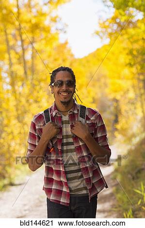 Stock Image - Mixed race man hiking in forest. Fotosearch