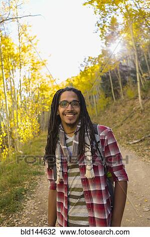 Stock Image - Mixed race man hiking in forest. Fotosearch