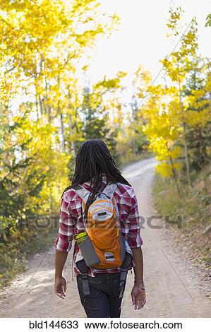 Stock Image - Mixed race man hiking in forest. Fotosearch