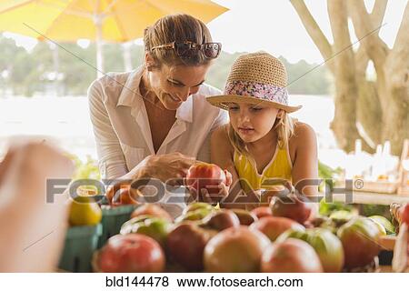 Mixed race mother and daughter browsing produce at farmers market View Large Photo Image Stock Photo - Mixed race mother and daughter browsing produce at farmers market. Fotosearch