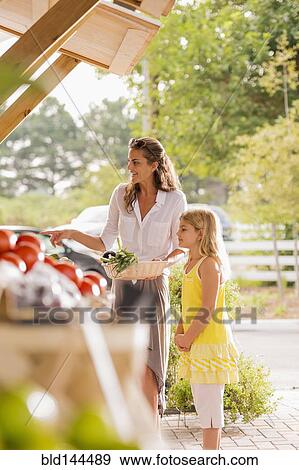 Mixed race mother and daughter browsing produce at farmers market View Large Photo Image Stock Photo - Mixed race mother and daughter browsing produce at farmers market. Fotosearch