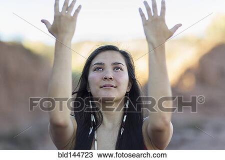 Stock Image - Mixed race woman meditating in desert. Fotosearch