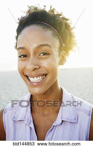 Stock Image - Mixed race woman smiling at beach. Fotosearch