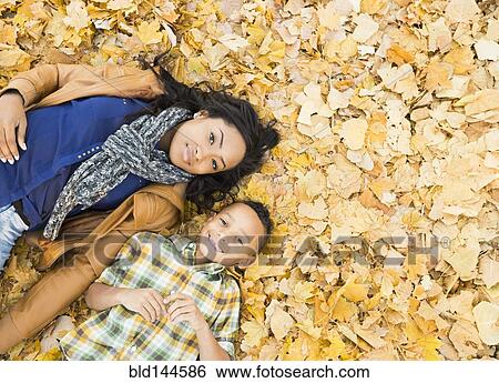 Mother and son laying together in autumn leaves View Large Photo Image Stock Photograph - Mother and son laying together in autumn leaves. Fotosearch