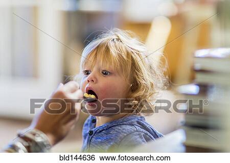 Stock Photograph - Mother feeding son at table. Fotosearch
