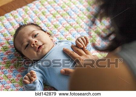 Stock Photo - Mother playing with baby boy on blanket. Fotosearch
