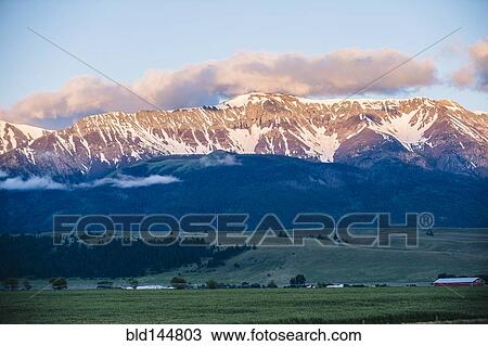 Stock Image - Mountains over farmlands in rural landscape. Fotosearch