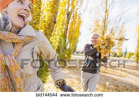 Picture - Older Caucasian couple playing with autumn leaves. Fotosearch
