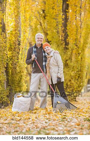 Stock Photo - Older Caucasian couple raking autumn leaves. Fotosearch