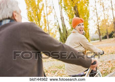 Stock Image - Older Caucasian couple riding bicycles on autumn leaves. Fotosearch